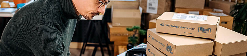 A person placing a USPS Ground Advantage package on a shelf in a delivery center.
